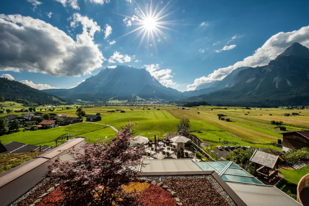 Sonnige Aussichtsterrasse des Hotel Hubertushof mit Panoramablick auf die grünen Wiesen und Berge.
